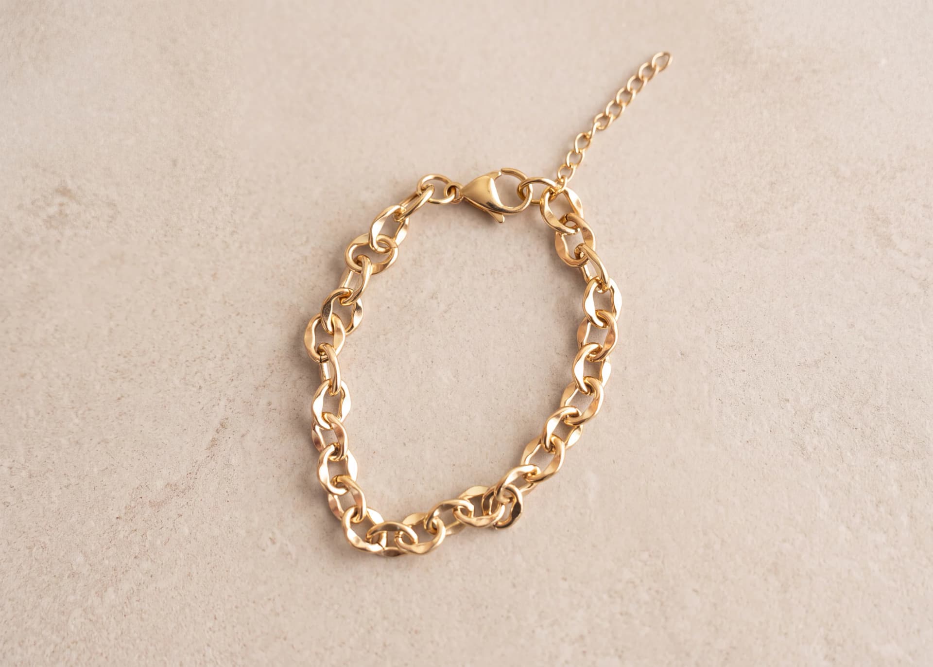 Gold-tone bracelet with twisted oval chain links shown flat with lobster clasp and extension chain